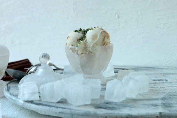 Homemade Organic white Vanilla Ice Cream with Nuts and ice cubes and big cinamonas. white cold background